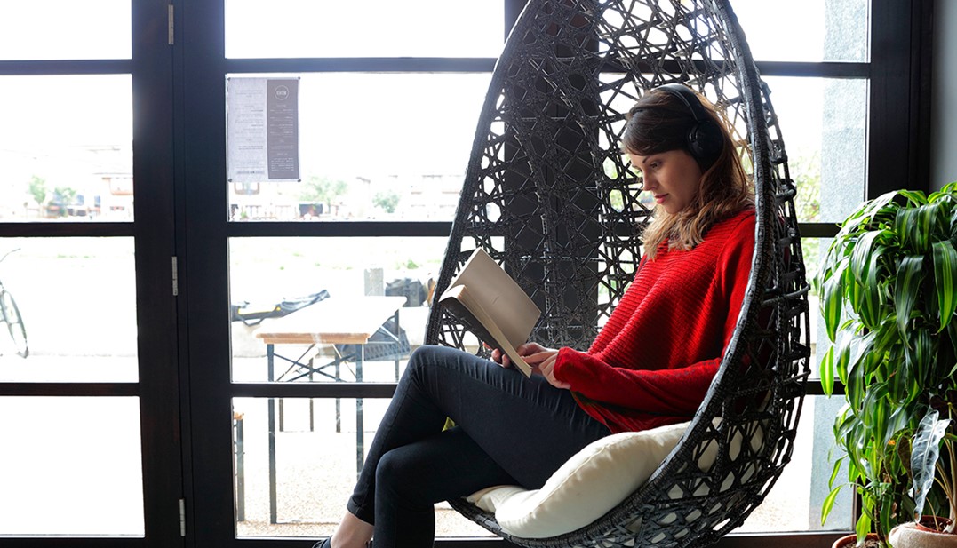 Mulher em cadeira de baçando lendo um livro. 